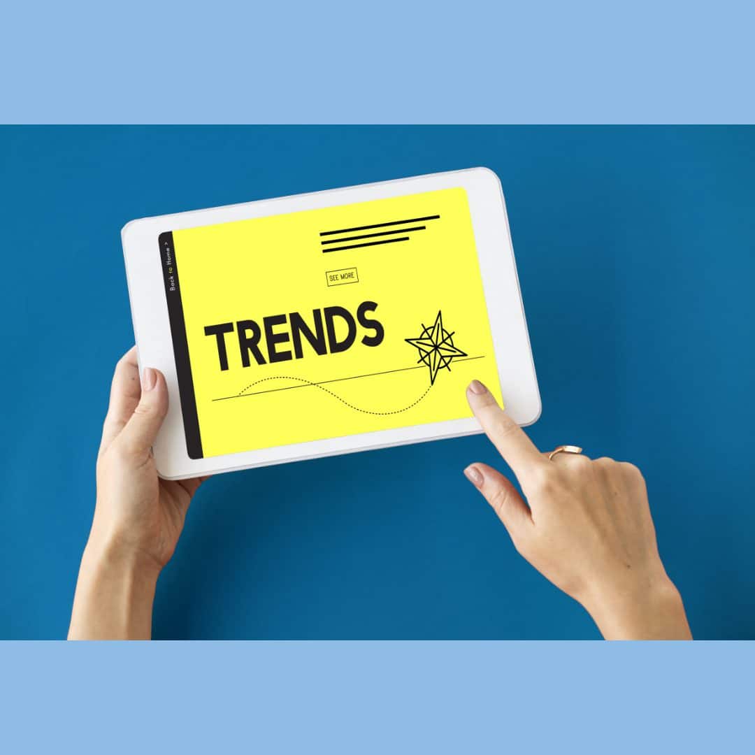 Hands holding a tablet, "trends" appears on the screen. Outsourcing market trends article
